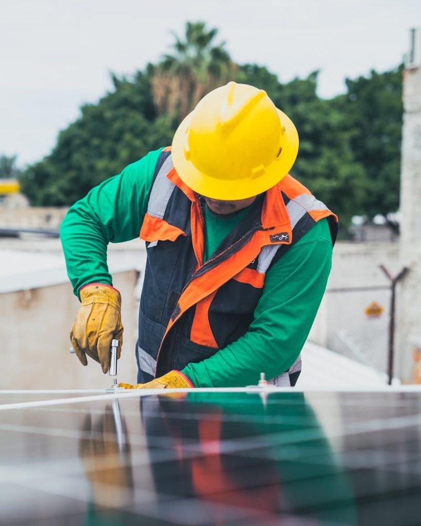 Photo by Los Muertos Crew Cristian Flore Aranjuez - Professional solar panel technician working outdoors with PPE.